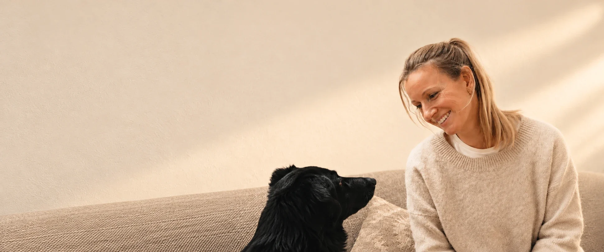Sylvia Schreiber, Hundephysiotherapeutin in Neuss, lächelt einen schwarzen Hund an, der ihr aufmerksam entgegensieht